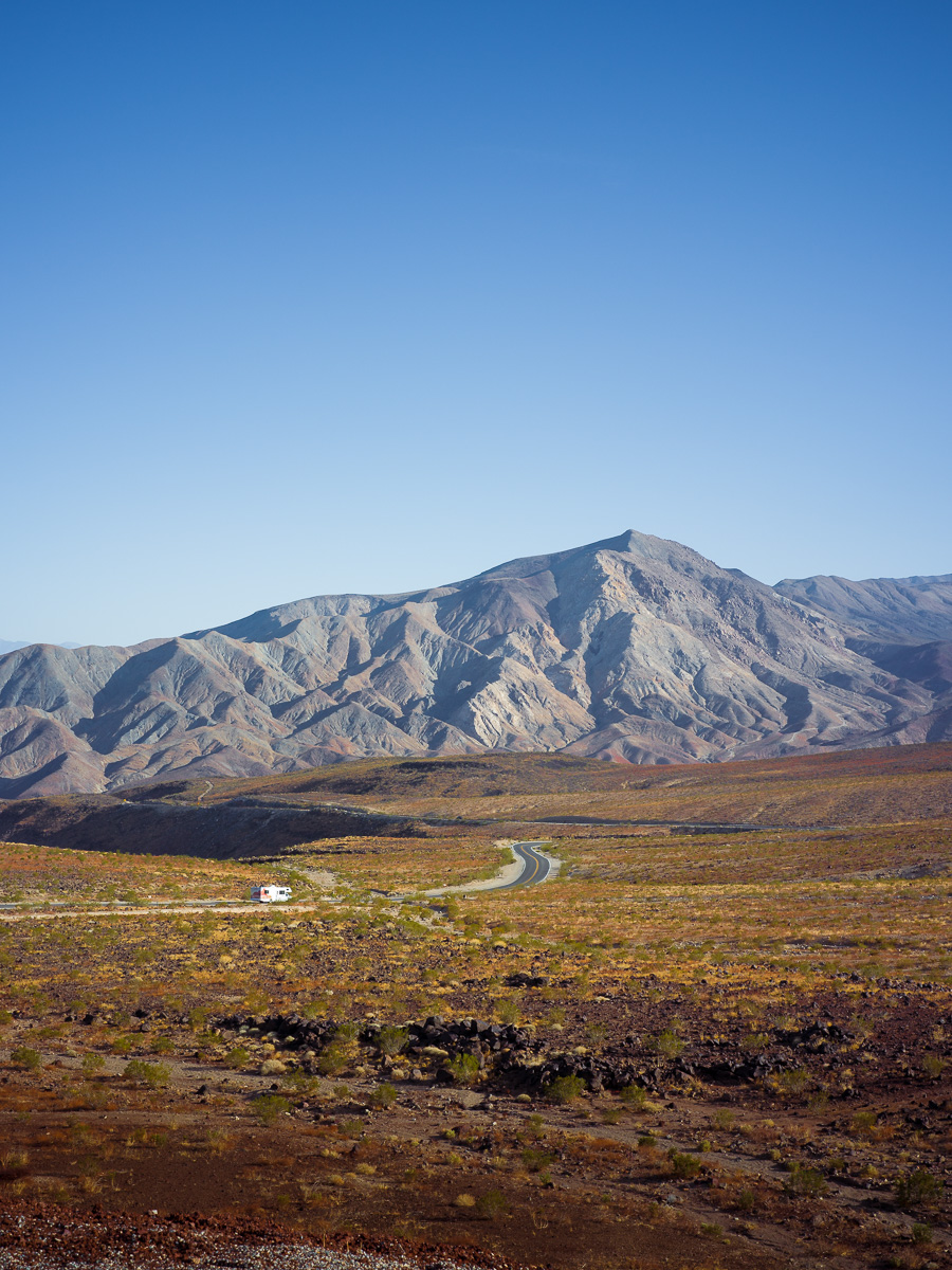 A solitary road winds through volcanic desert toward barren Death Valley peaks.