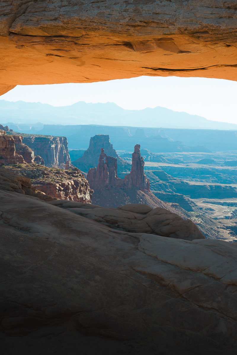 Mesa Arch frames sunlit spires and layered canyons in morning light.