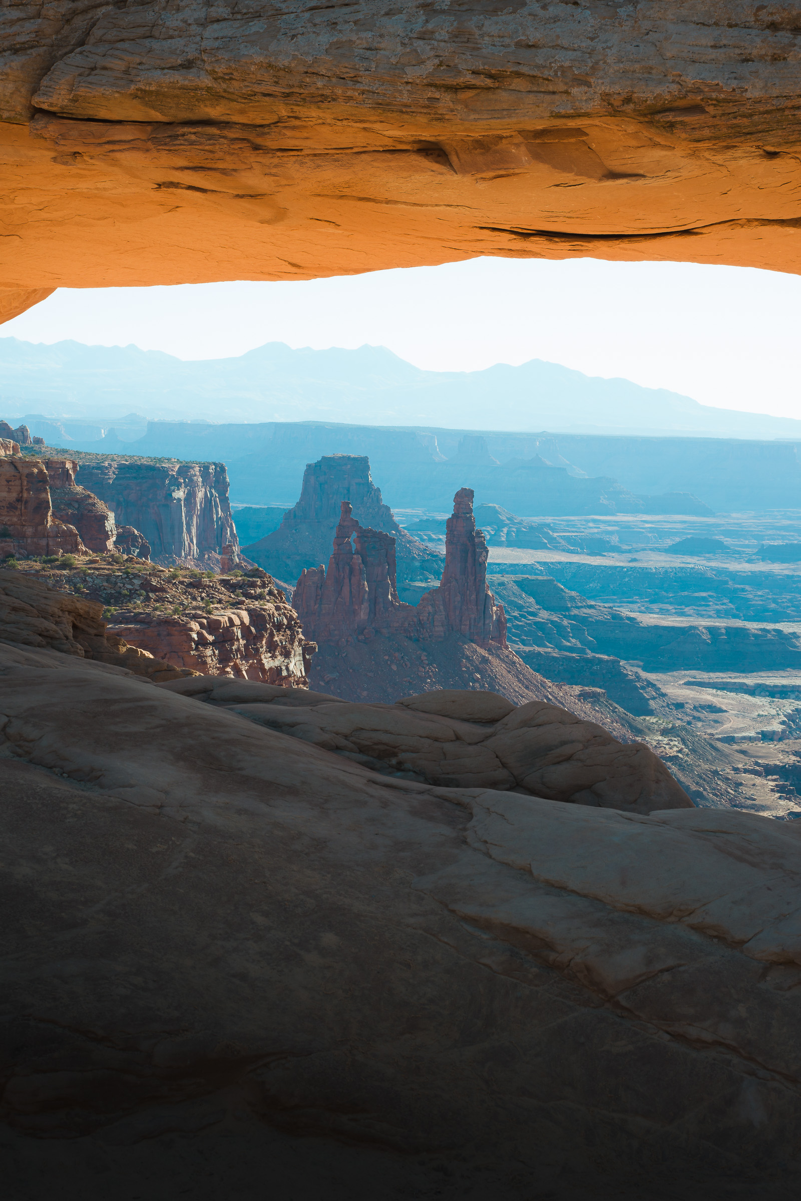 Mesa Arch frames sunlit spires and layered canyons in morning light.