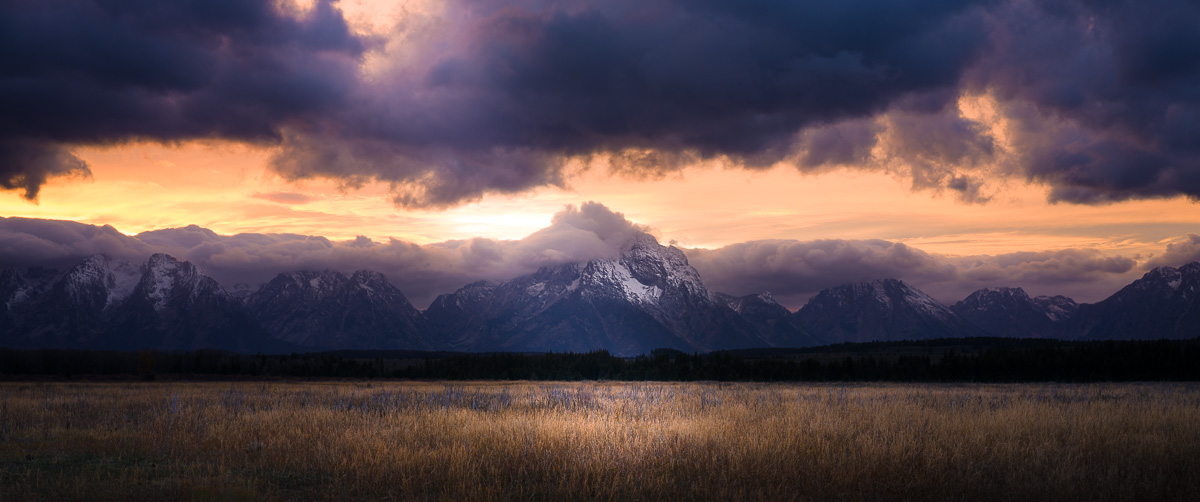Dramatic sunset crowns the Teton Range as golden meadows glow below.