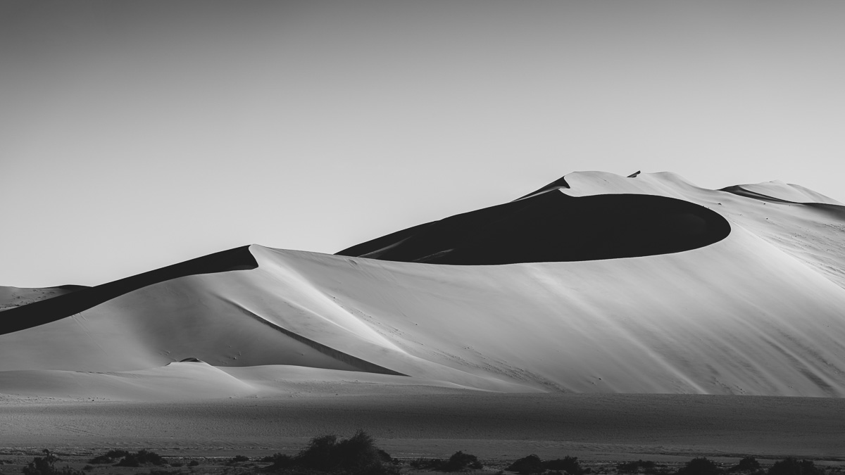 Monumental dunes rendered in silver and shadow, stripped to pure form.