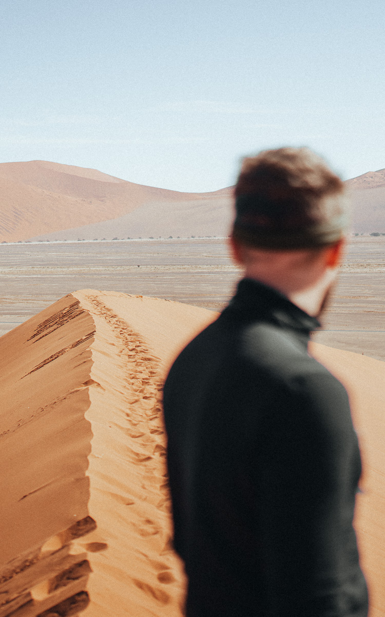 A traveler surveys the endless dune sea from a windswept crest.